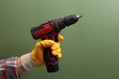 Photo of Handyman holding electric screwdriver on pale green background, closeup