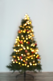 Blurred view of beautiful Christmas tree with fairy lights, indoors