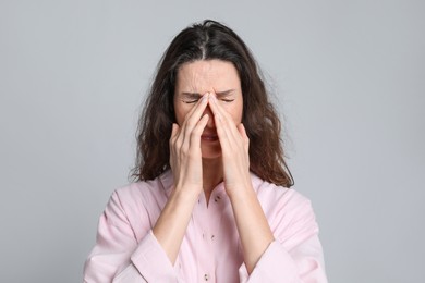 Photo of Mature woman suffering from headache on light grey background