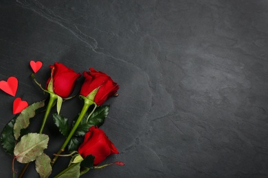 Photo of Beautiful red roses and paper hearts on black background, flat lay with space for text. Valentine's Day celebration