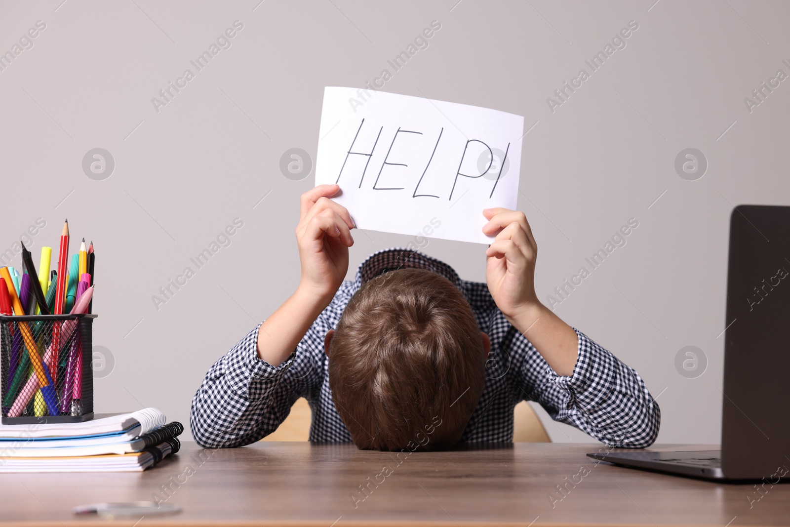 Photo of Dyslexia concept. Little boy holding paper with word Help at wooden table