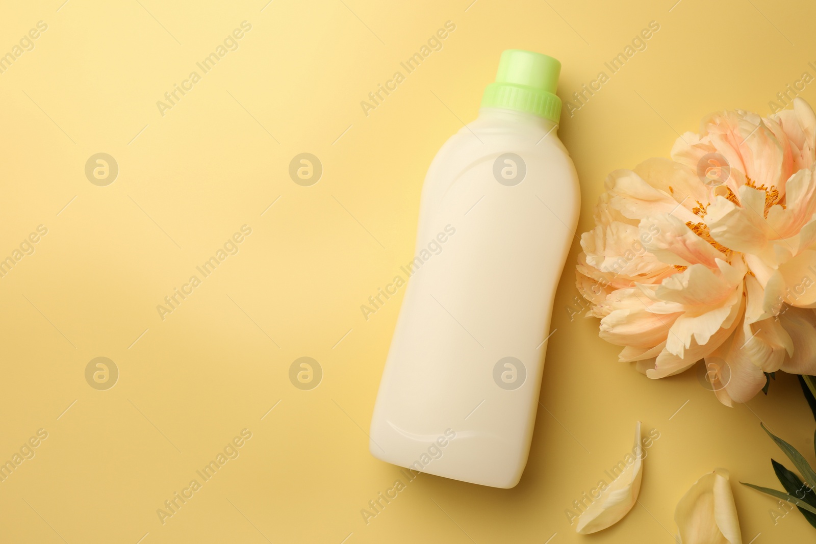 Bottle of fabric softener and beautiful peony flower on pale yellow background, flat lay. Space for text Photo of Bottle of fabric softener and beautiful peony flower on pale yellow background, flat lay. Space for text