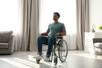 Young man sitting in modern wheelchair indoors