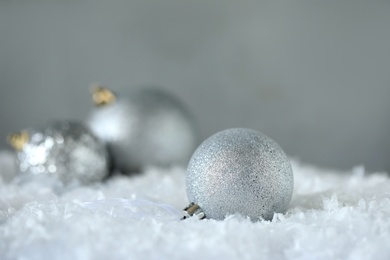 Photo of Beautiful Christmas ball on snow against grey background. Space for text