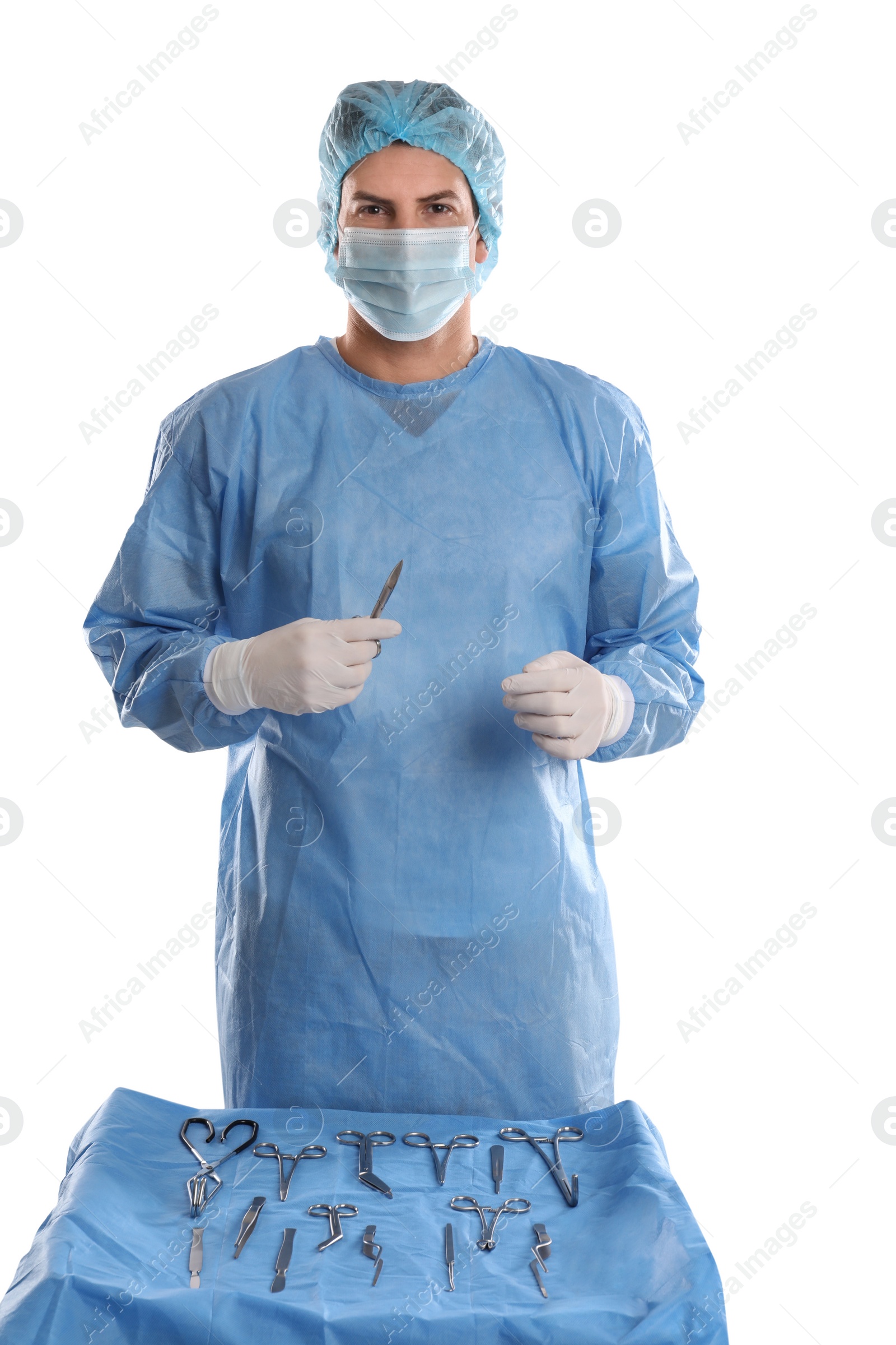 Photo of Doctor holding Mayo scissors near table with different surgical instruments on light background