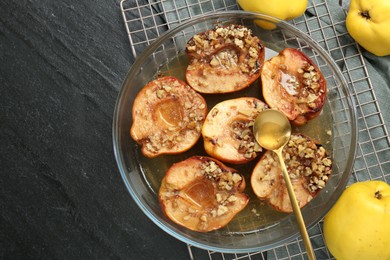 Photo of Tasty baked quinces with walnuts and honey in bowl on black table, flat lay. Space for text