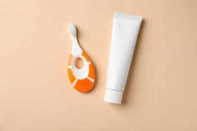 Photo of Baby toothbrush and toothpaste on color background, top view