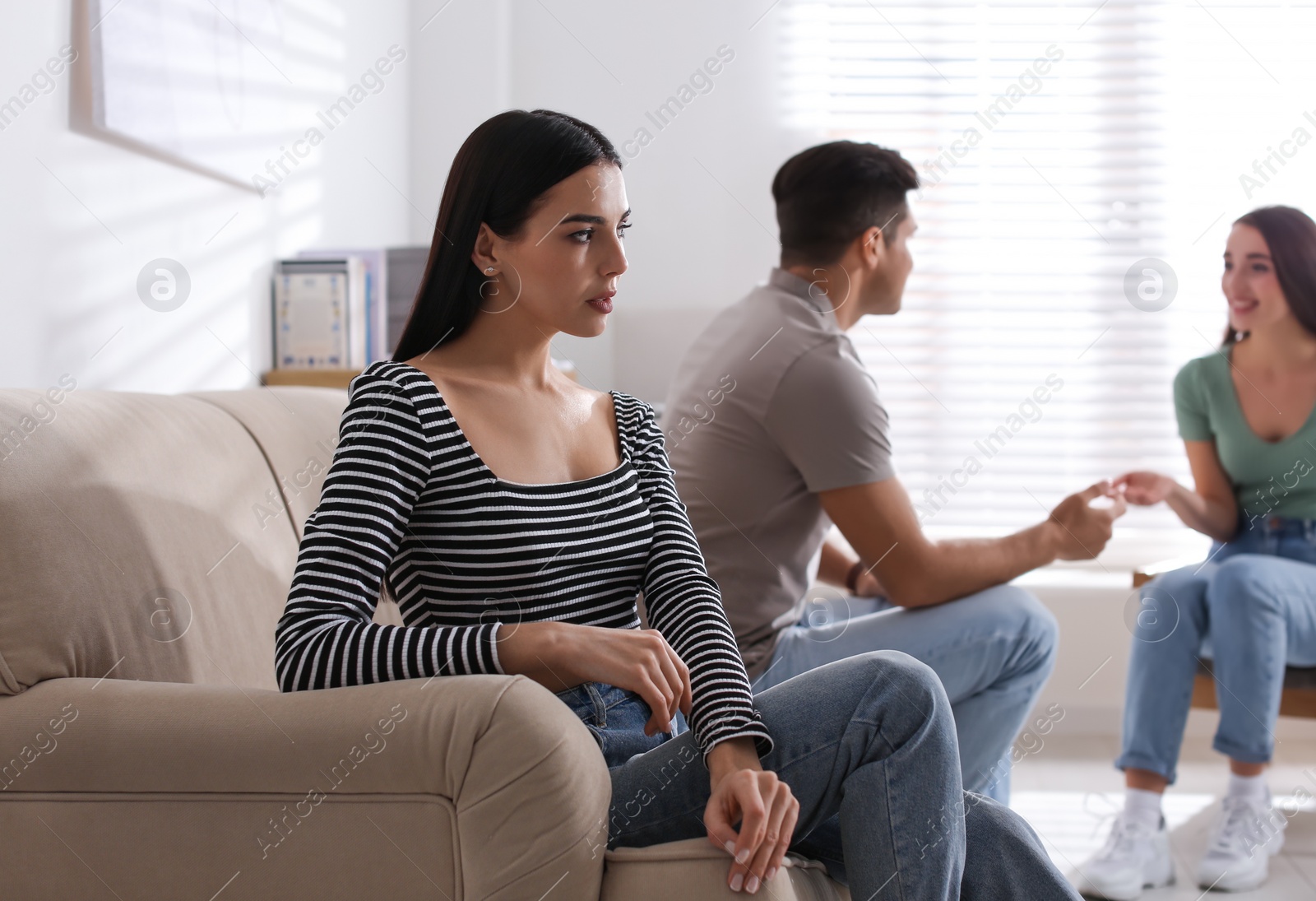 Photo of Unhappy woman feeling jealous while couple spending time together at home