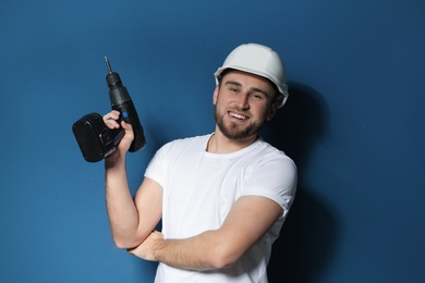Photo of Young working man with electric screwdriver on color background