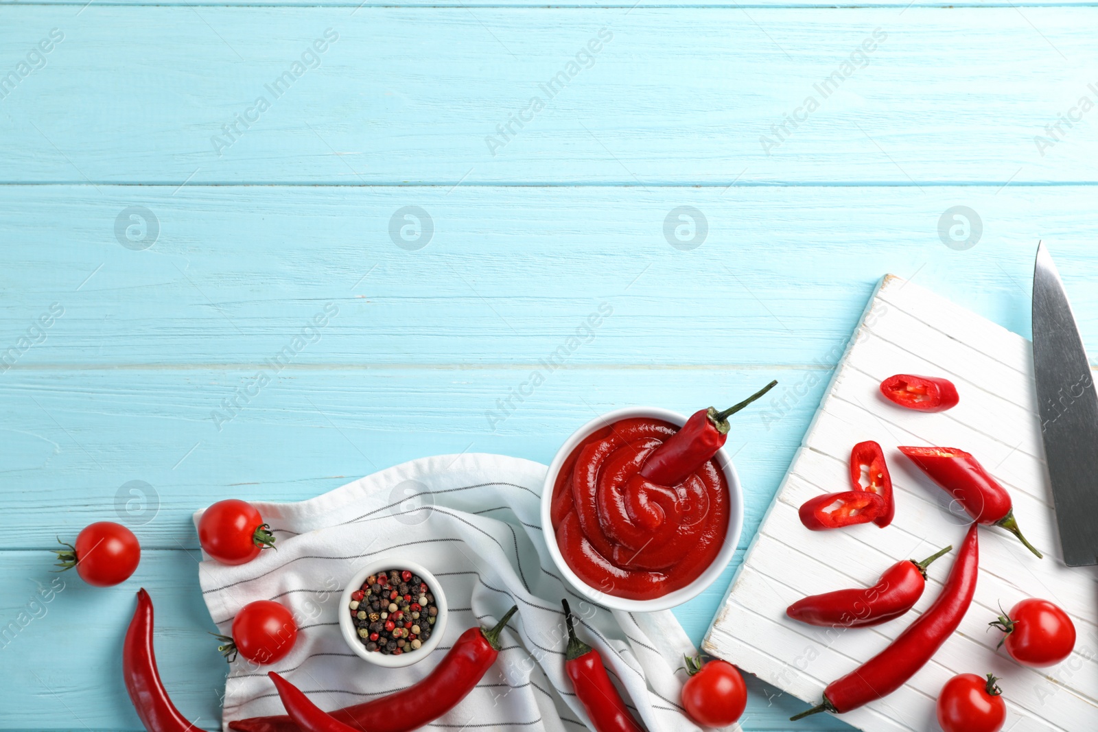 Photo of Flat lay composition with bowl of hot chili sauce on wooden background