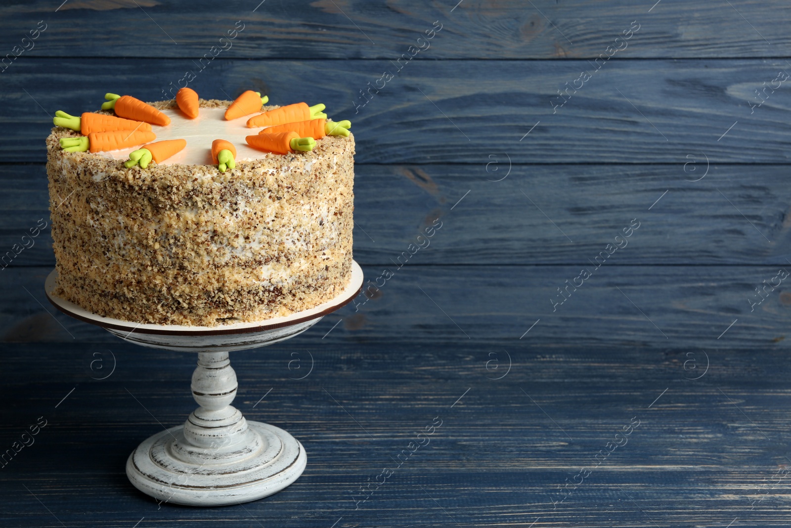 Photo of Stand with delicious carrot cake on blue wooden background, space for text