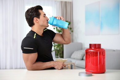 Young athletic man drinking protein shake at home