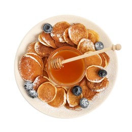 Photo of Delicious mini pancakes cereal with blueberries and honey on white background, top view