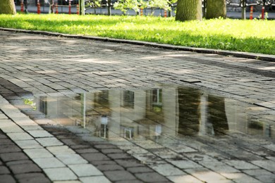 Photo of Puddle after rain on street tiles outdoors