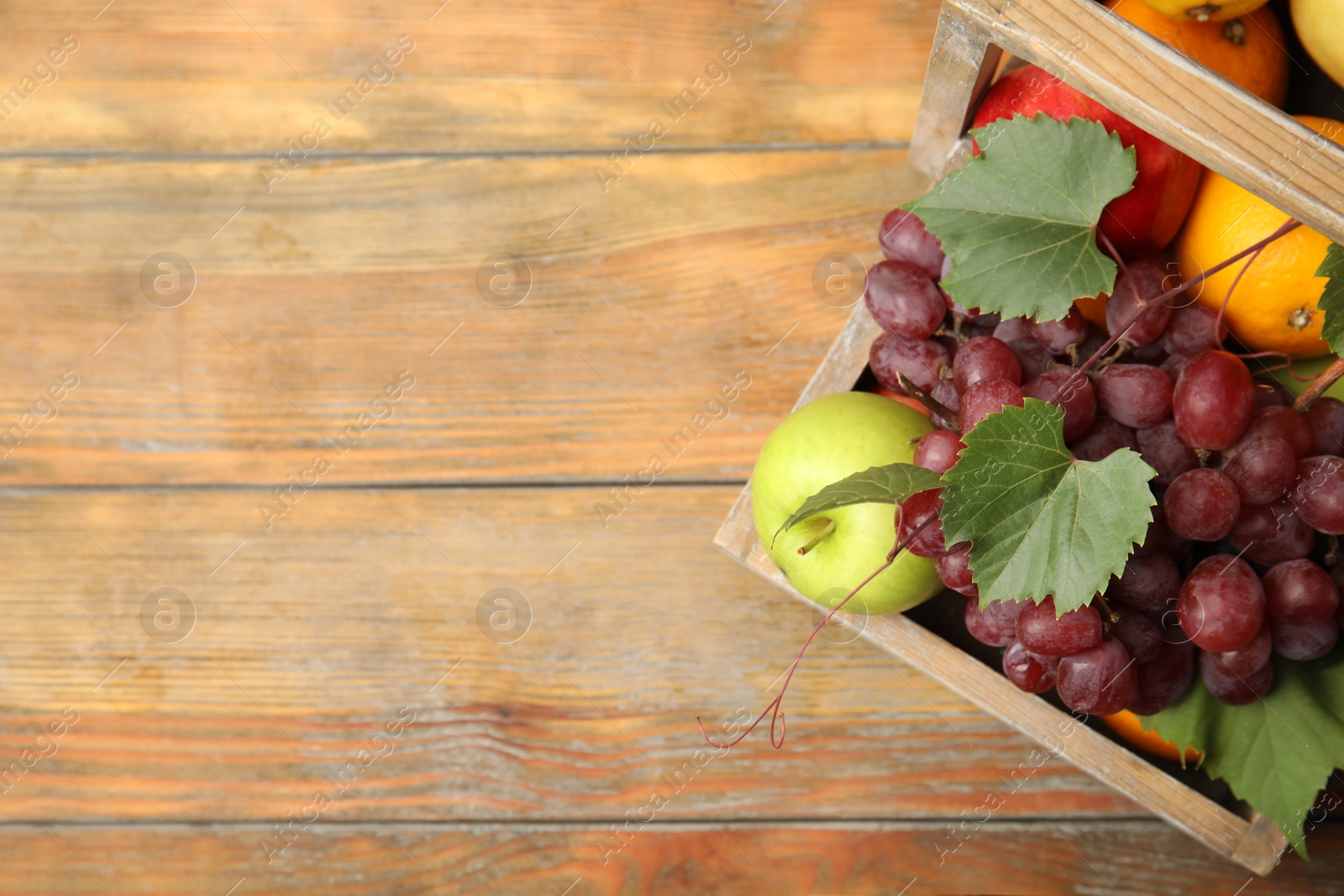 Photo of Crate with different fruits on wooden table, top view. Space for text