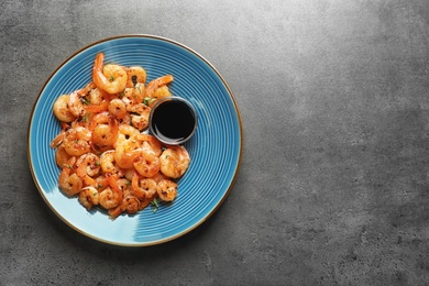 Photo of Plate with fried shrimps and soy sauce on grey background