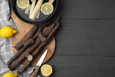 Photo of Raw salsify roots with lemon on grey wooden table, flat lay. Space for text