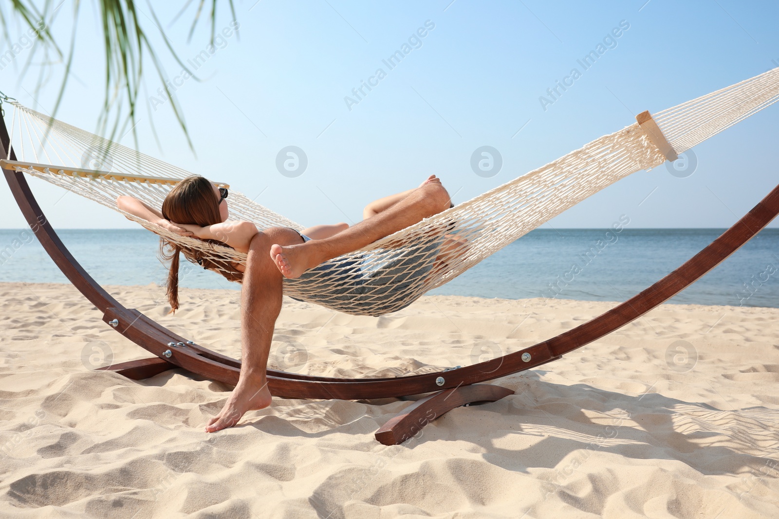 Photo of Young lovely relaxing in hammock on beach