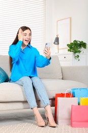 Special Promotion. Emotional woman with smartphone on sofa indoors