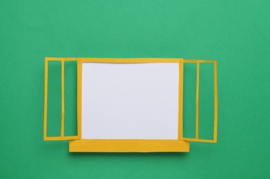 Photo of Open paper window frame on green background. Space for text