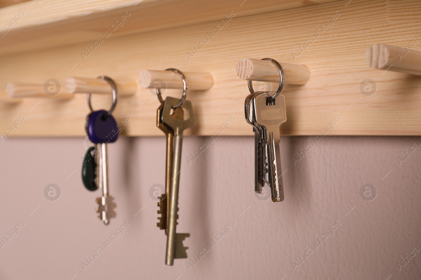 Photo of Wooden hanger for keys on color wall, closeup