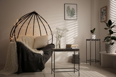 Cozy hanging chair with fairy lights in modern living room. Interior design