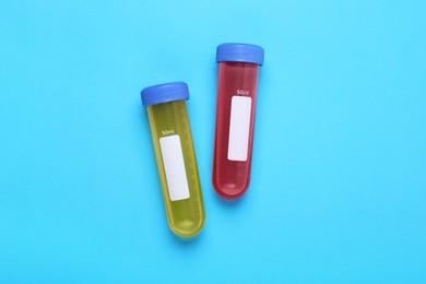 Test tubes with colorful liquids on light blue background, flat lay. Kids chemical experiment set