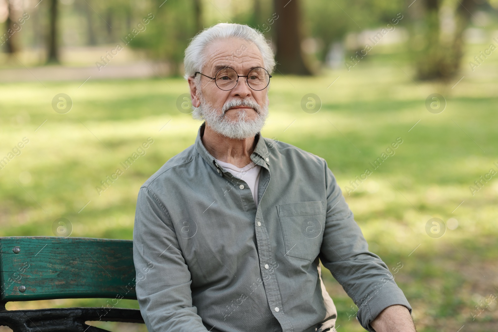 Photo of Portrait of happy grandpa with glasses on bench in park