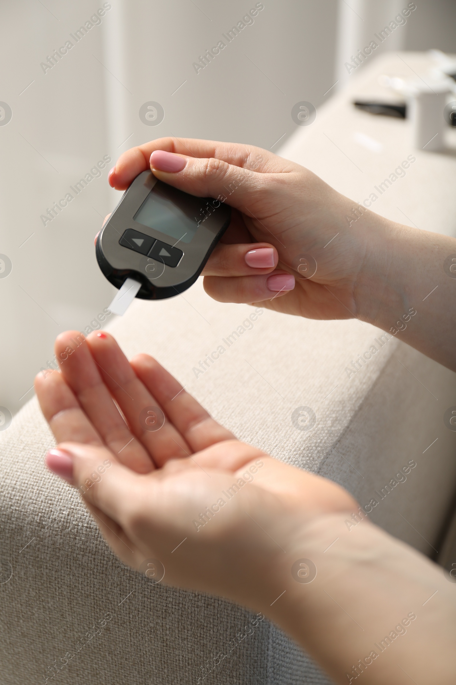 Photo of Diabetes. Woman checking blood sugar level with glucometer at home, closeup