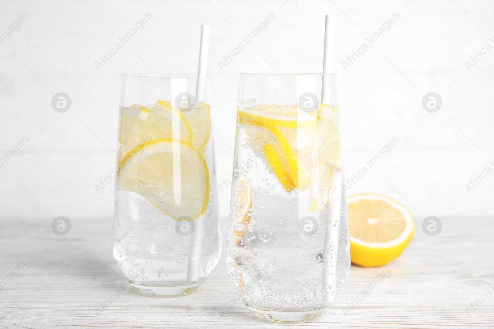 Photo of Soda water with lemon slices and fresh fruit on white wooden table