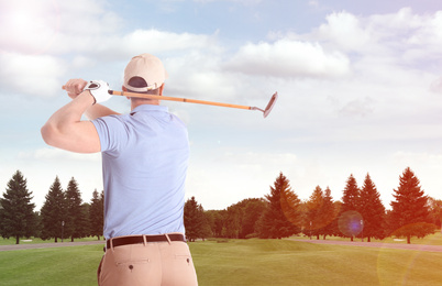 Image of Young man playing golf on course with green grass, back view. Space for design