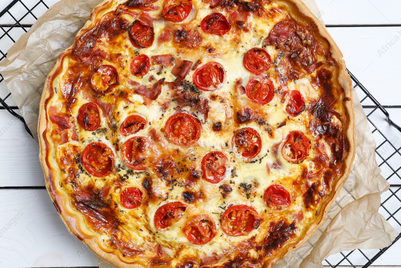 Photo of Delicious homemade quiche with prosciutto and tomatoes on wooden table, top view