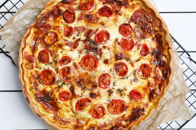 Delicious homemade quiche with prosciutto and tomatoes on wooden table, top view