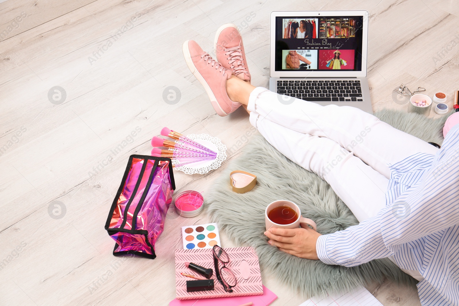 Photo of Beauty blogger with laptop and cosmetics sitting on floor, closeup