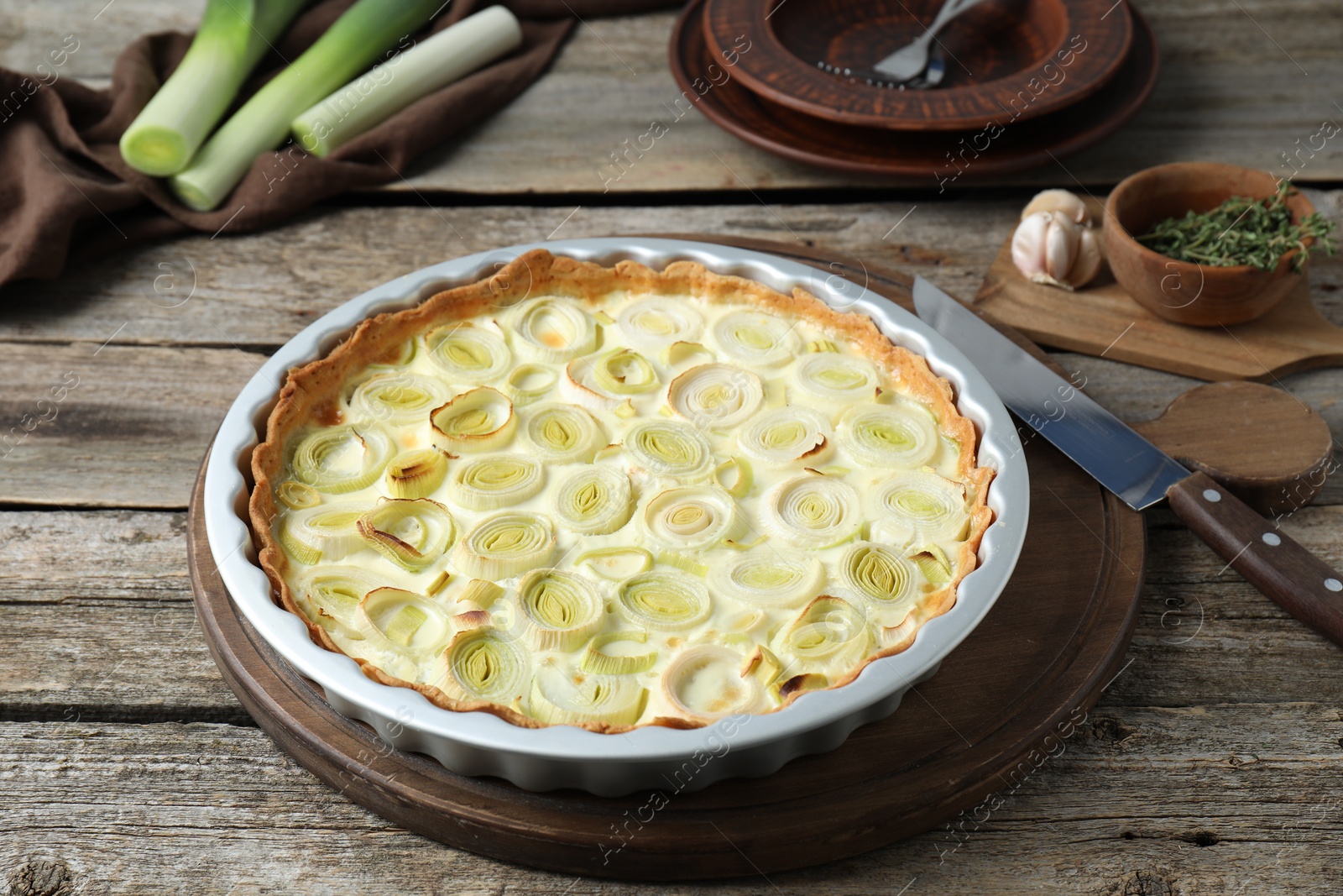 Photo of Tasty leek pie, knife and products on old wooden table