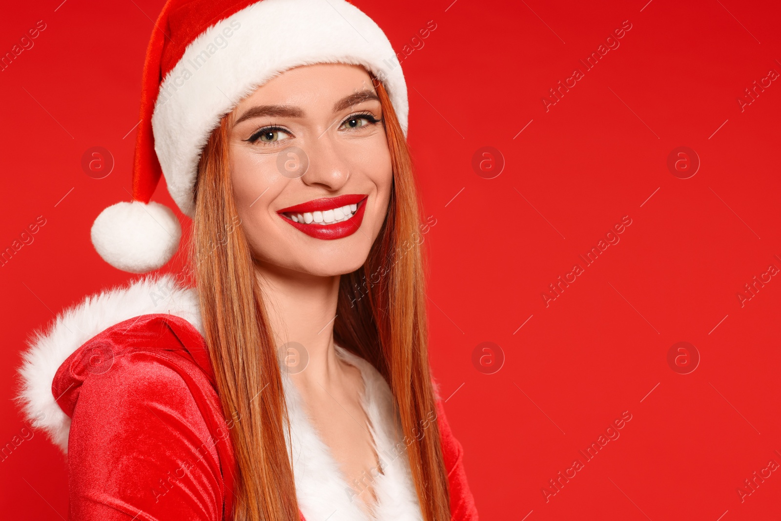 Photo of Young woman in Santa hat on red background, space for text. Christmas celebration