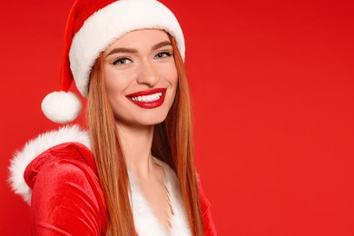 Young woman in Santa hat on red background, space for text. Christmas celebration