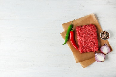 Photo of Fresh raw minced meat on white wooden table, top view. Space for text
