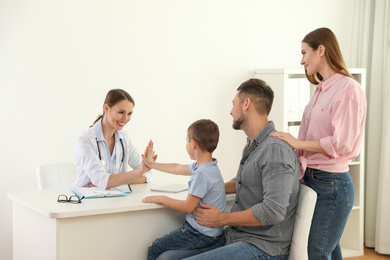 Photo of Parents and son visiting pediatrician. Doctor working with patient in hospital