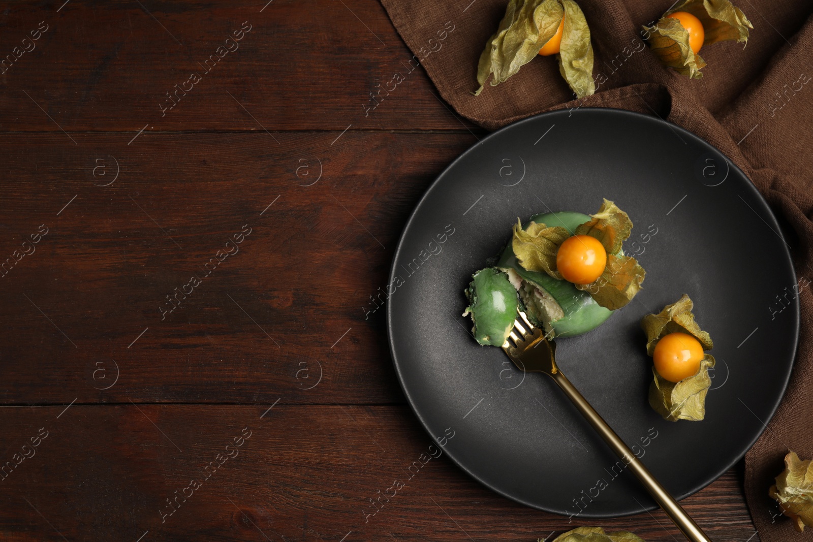 Photo of Delicious mousse cake decorated with physalis fruit on wooden table, flat lay. Space for text