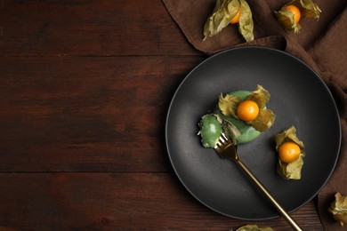 Delicious mousse cake decorated with physalis fruit on wooden table, flat lay. Space for text