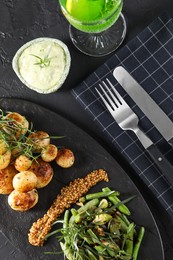 Delicious salad with tarragon, mustard and grilled potatoes served on black textured table, flat lay