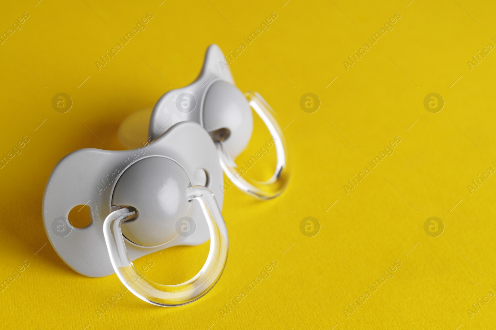 Photo of New baby pacifiers on yellow background. Space for text