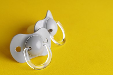 Photo of New baby pacifiers on yellow background. Space for text