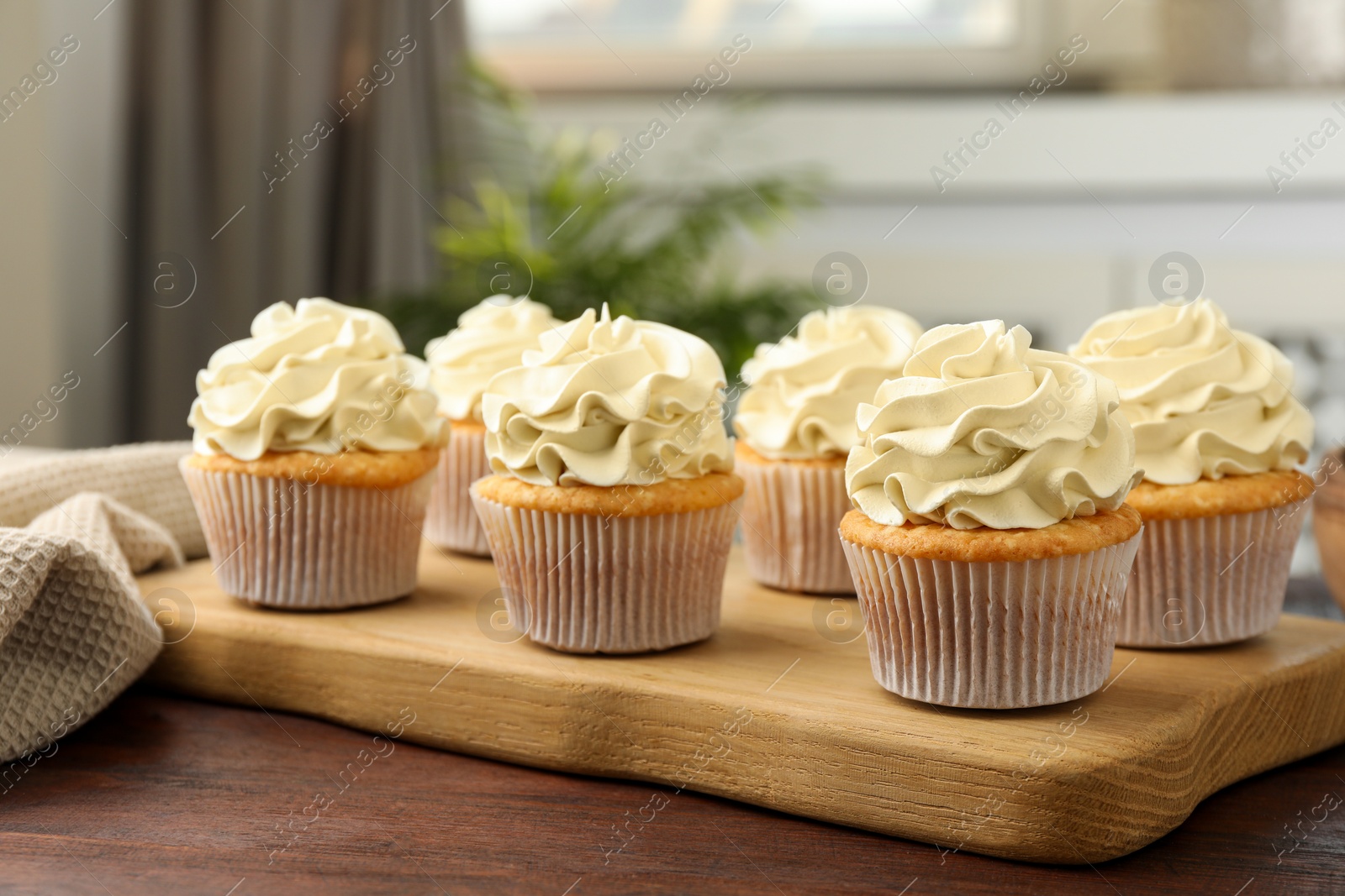 Photo of Tasty cupcakes with vanilla cream on wooden table, closeup