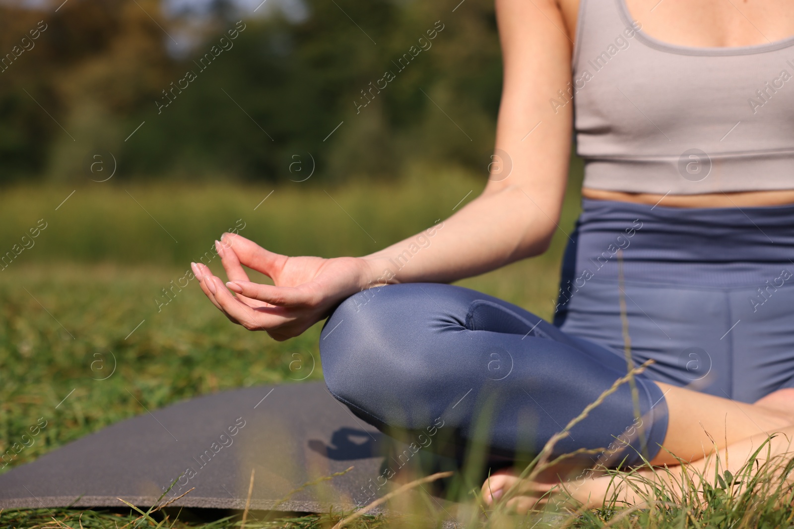 Photo of Woman practicing yoga on mat outdoors, closeup and space for text. Lotus pose