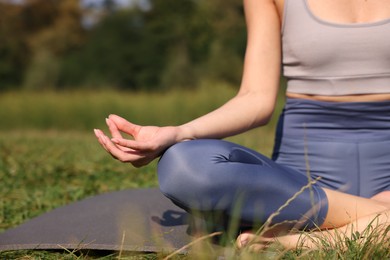 Photo of Woman practicing yoga on mat outdoors, closeup and space for text. Lotus pose