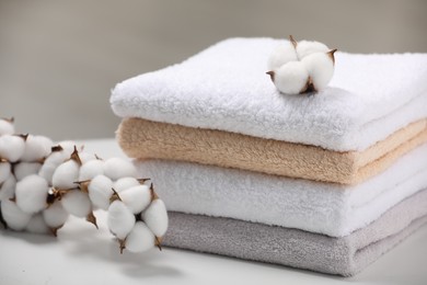 Terry towels and cotton branch with fluffy flowers on white table, closeup
