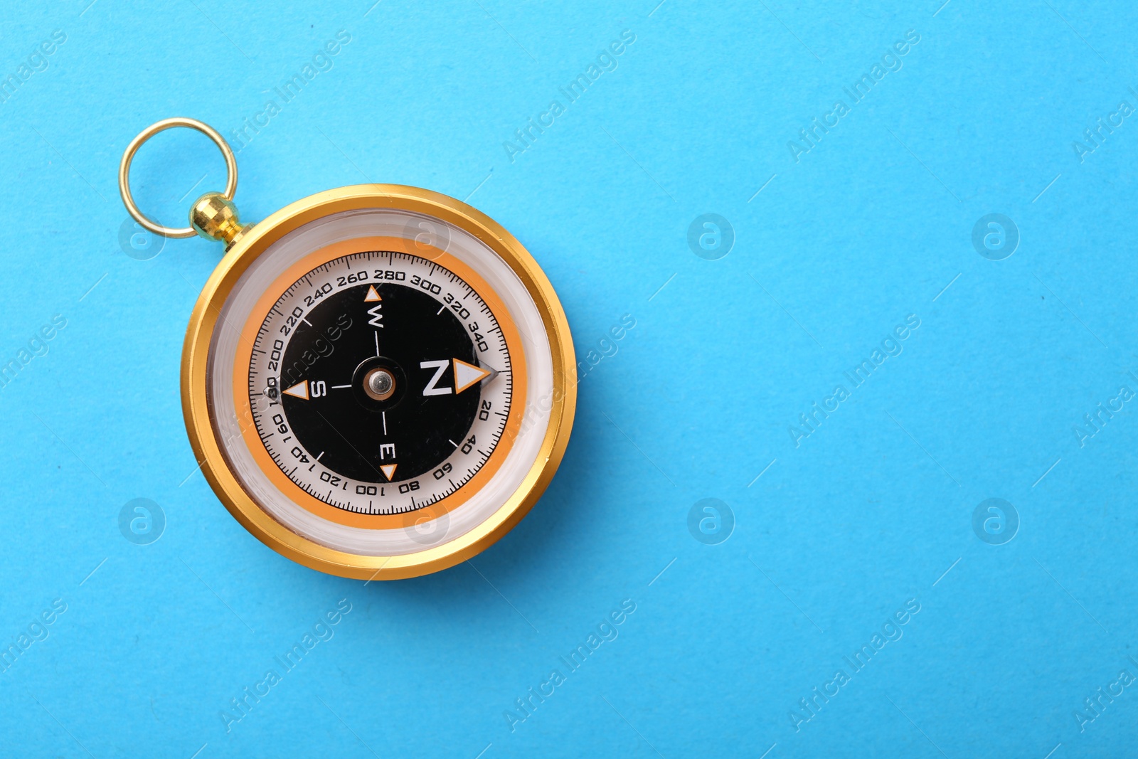 Photo of Compass on light blue background, top view. Space for text