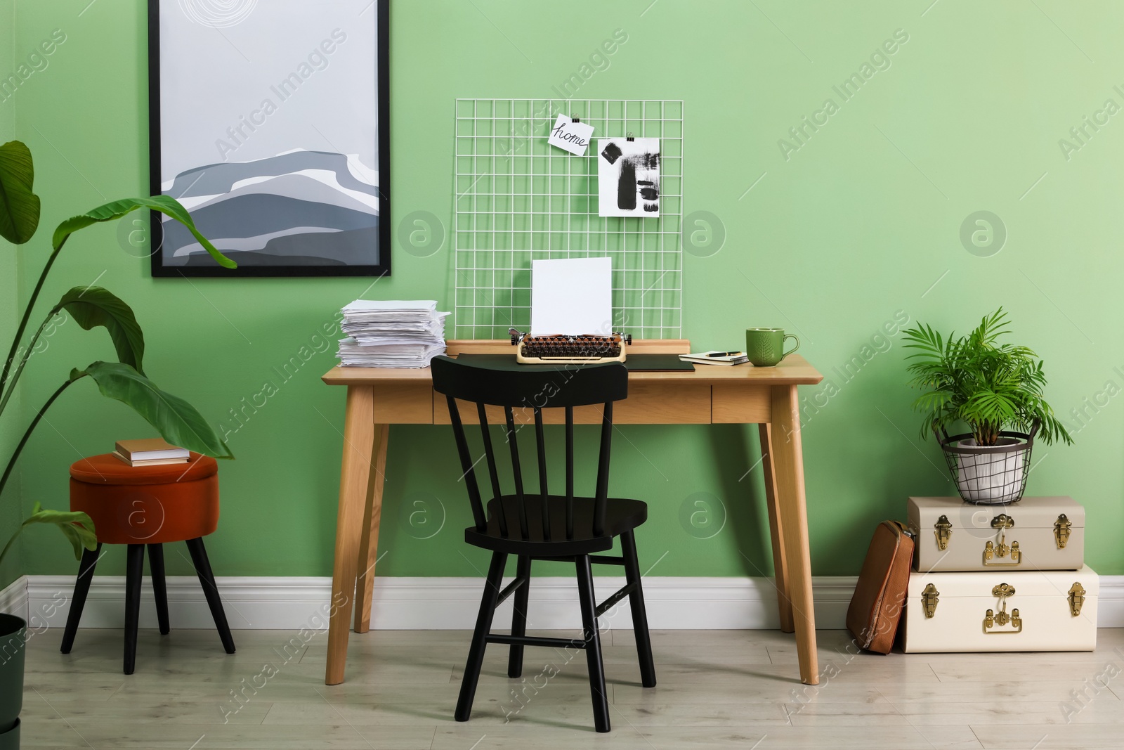 Photo of Typewriter, stack of papers and mood board on wooden table near pale green wall. Writer's workplace